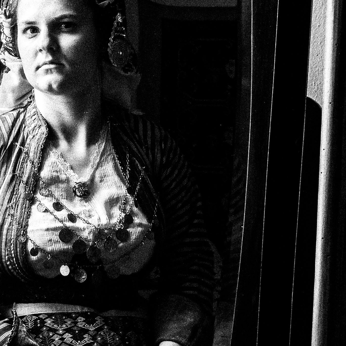 Woman looking at herself in a mirror in Soufli, Thrace, Greece, with a vintage photograph on the wall. Black and white photography close-up detail by George Tatakis