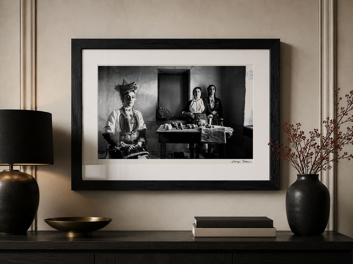 Framed black and white portrait by George Tatakis on a wall above a wooden console table.