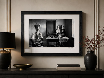 Framed black and white portrait by George Tatakis on a wall above a wooden console table.
