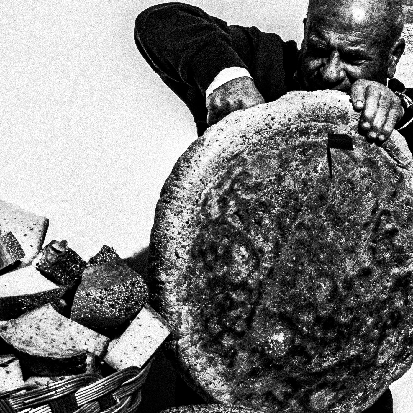 Black and White Photography Wall Art Greece | Cutting bread during a feast in Tristomo Olympos Karpathos Dodecanese by George Tatakis - detailed view