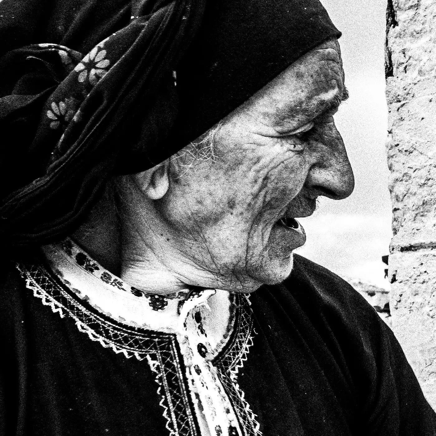 Black and White Photography Wall Art Greece | Woman spreading the fire inside wood oven in her traditional costume Olympos Karpathos by George Tatakis - detailed view