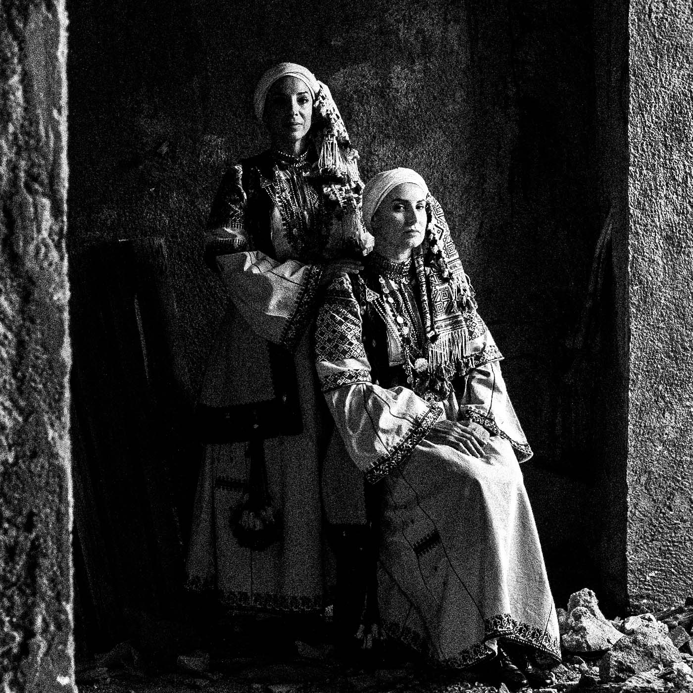 Woman in profile and two supporting figures in Kyparissia costumes, Peloponnese, Greece. Black and white photography close-up detail by George Tatakis.