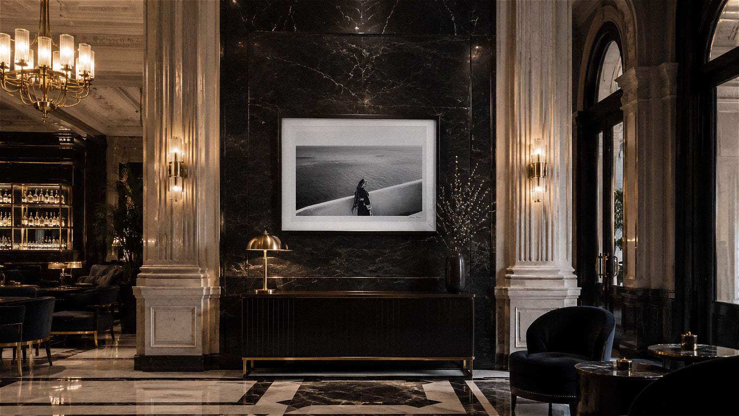 Luxurious interior with marble walls, chandelier, and framed black and white photography print in a high-end establishment. By George Tatakis.