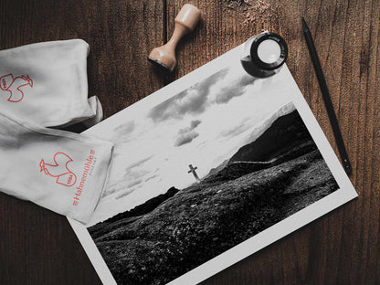 Cross on a rock at Meteora. Black-and-white photography artwork by George Tatakis from the project Chorōs. Print on a wooden table