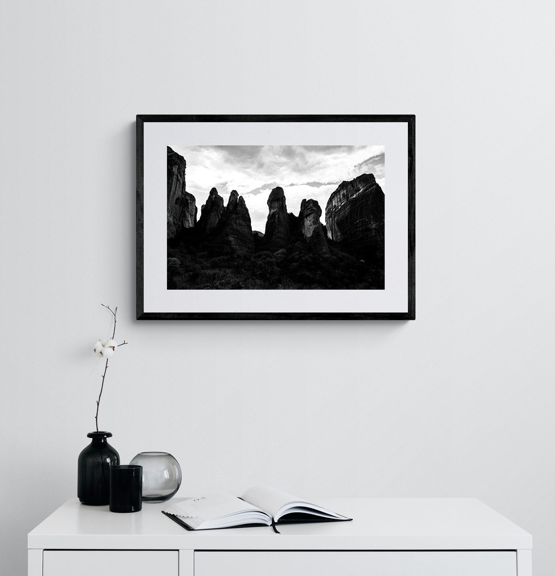 Meteora pillar formations. Black-and-white photography print by George Tatakis, from the project Chorōs. Framed on a white wall