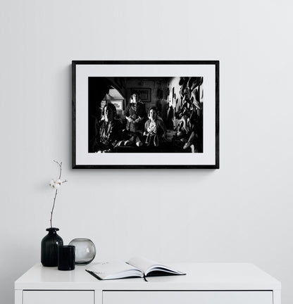 Three women in a room with shelves and shoes. Traditional costumes of Soufli, Thrace, Greece. Black and white photography framed on a wall by George Tatakis