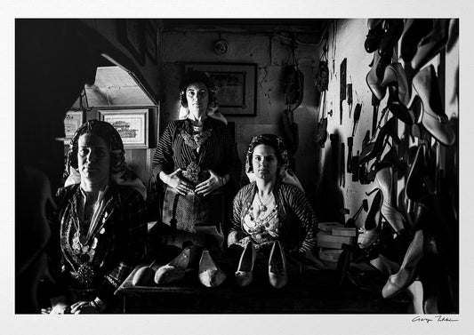 Three women in a room with shelves and shoes. Traditional costumes of Soufli, Thrace, Greece. Black and white photography by George Tatakis