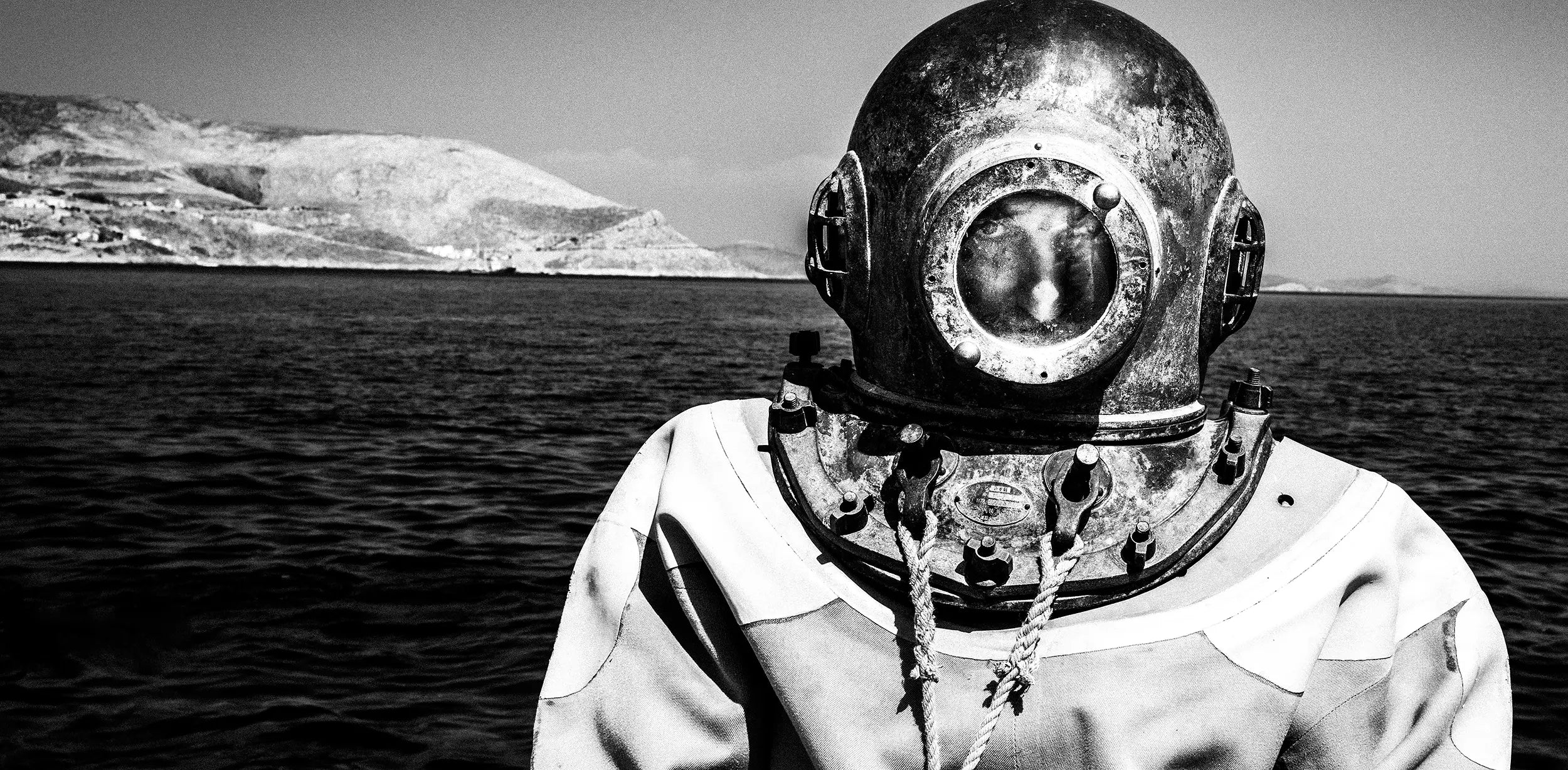 Black and white photography by George Tatakis of a man wearing a traditional sponge-diving suit on Kalymnos, Greece.