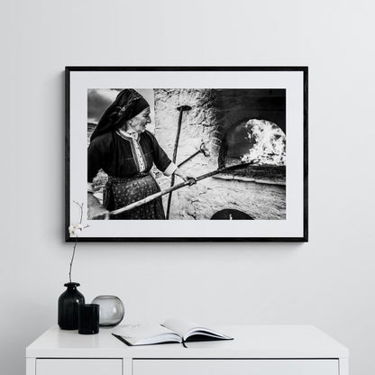 Black and White Photography Wall Art Greece | Woman spreading the fire inside wood oven in her traditional costume Olympos Karpathos by George Tatakis - single framed photo
