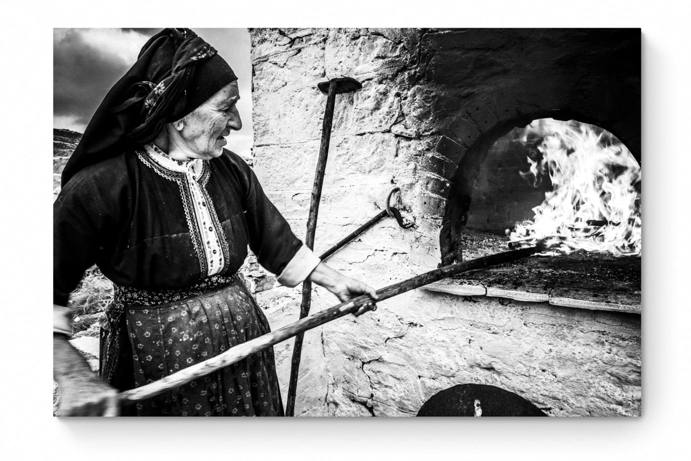 Black and White Photography Wall Art Greece | Woman spreading the fire inside wood oven in her traditional costume Olympos Karpathos by George Tatakis - whole photo