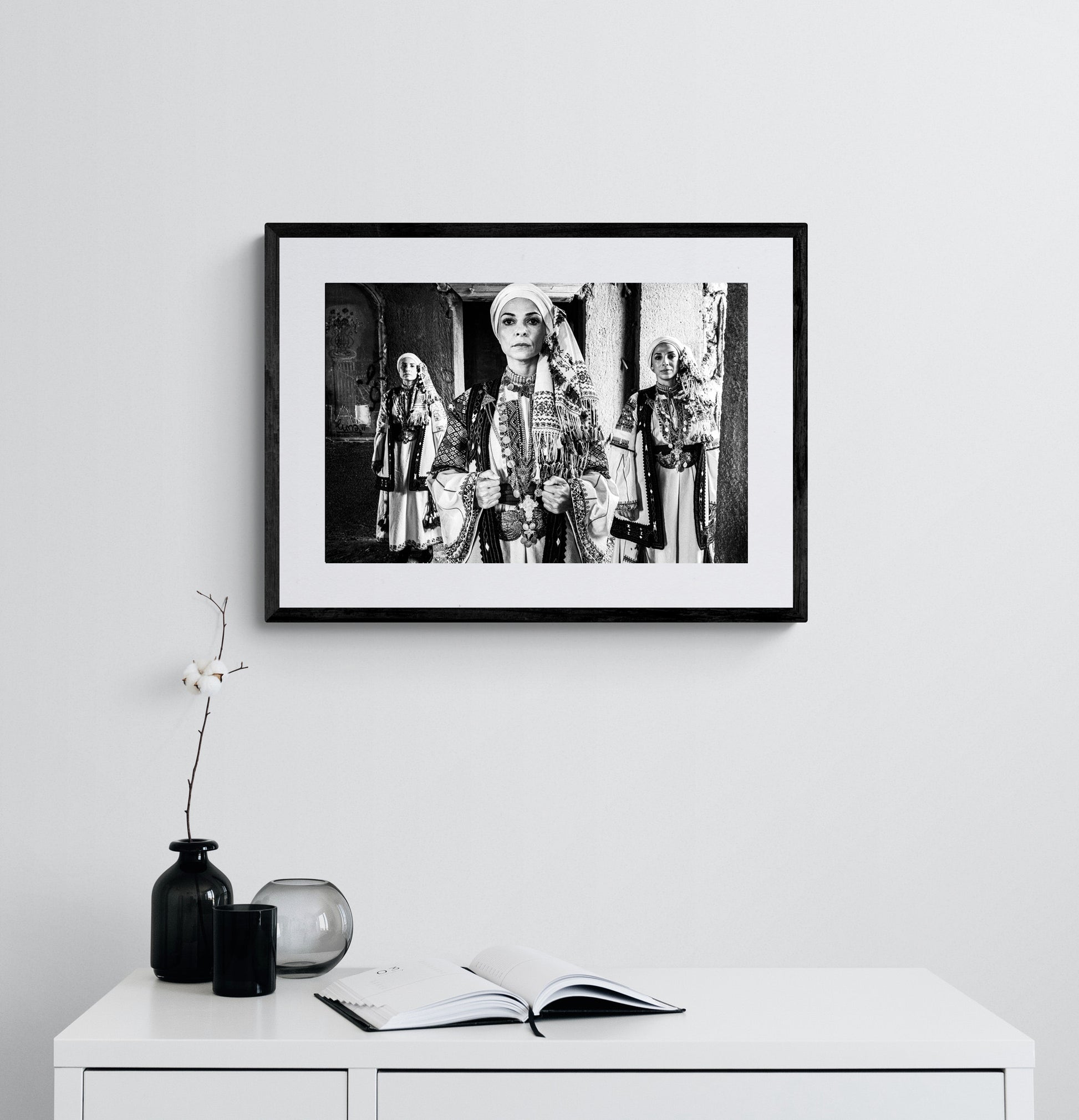 Three women in traditional attire standing in a doorway. Kyparissia, Peloponnese, Greece. Black and white photography framed on a wall by George Tatakis.