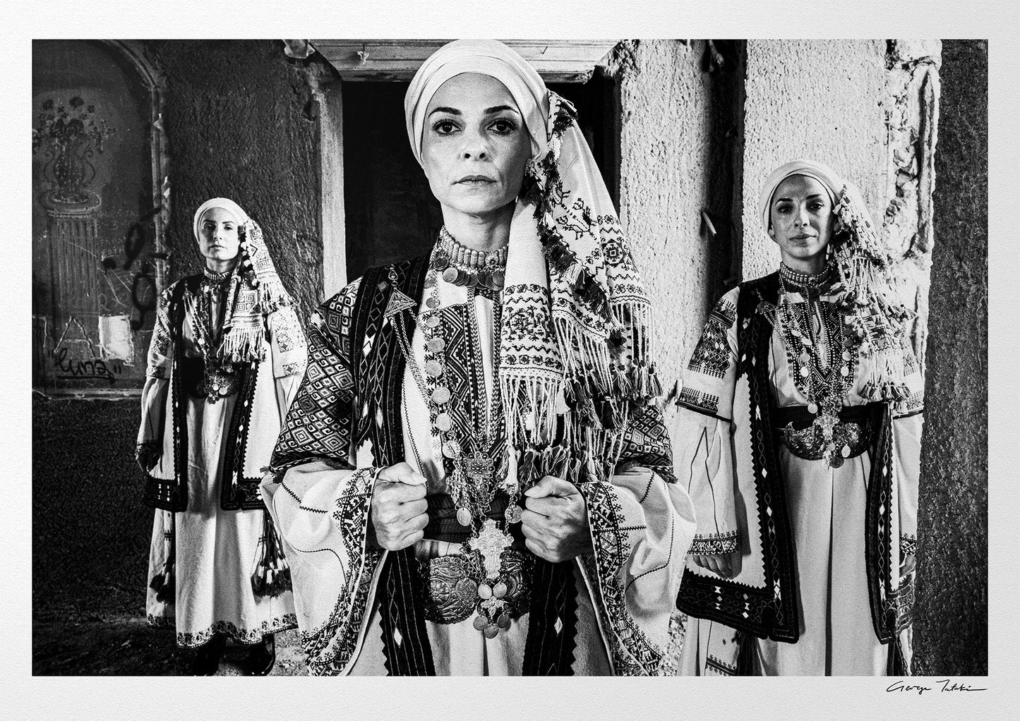 Three women in traditional attire standing in a doorway. Kyparissia, Peloponnese, Greece. Black and white photography by George Tatakis.