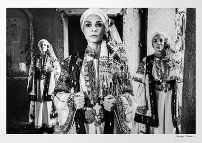 Three women in traditional attire standing in a doorway. Kyparissia, Peloponnese, Greece. Black and white photography by George Tatakis.