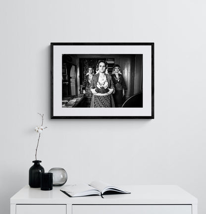Black and white portrait of a woman in traditional attire with two other women in the background. Soufli local dresses, Thrace, Greece. Photography framed on a wall by George Tatakis
