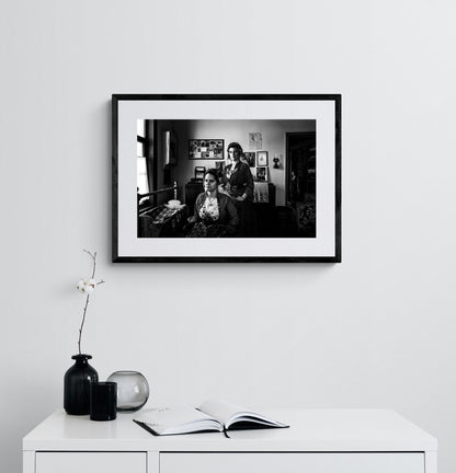Two women in a room with framed pictures on the wall. Local dresses of Soufli, Thrace, Greece. Black and white photography framed on a wall by George Tatakis.