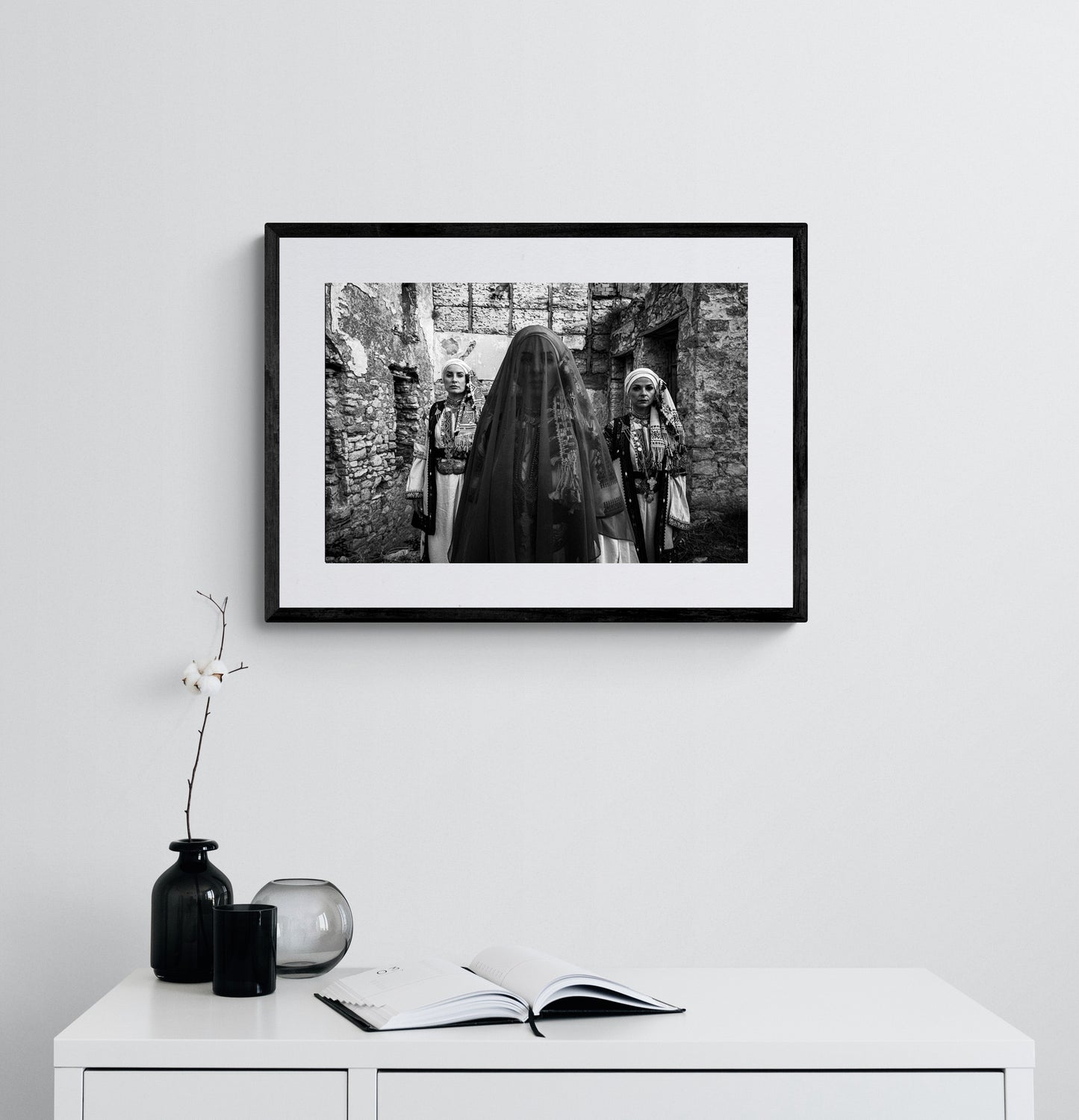 Three women in traditional attire standing in stone-walled ruins. Kyparissia, Peloponnese, Greece. Black and white photography framed on a wall by George Tatakis.